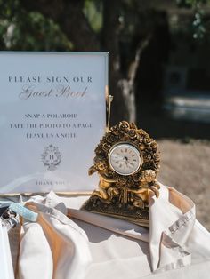 a clock sitting on top of a table next to a sign that says please sign our guest book