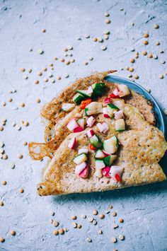 two pieces of pita bread with veggies on top and chickpeas in the background