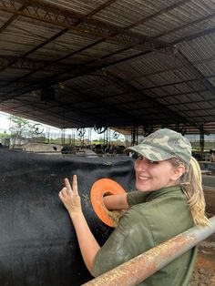 a woman is petting a black cow in an enclosed area with metal bars on it