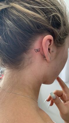 a woman with a small butterfly tattoo on her left ear