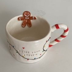 a ceramic cup with a gingerbread man on it's side and candy canes in the bottom