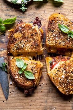 four pieces of bread with cheese and herbs on them next to a knife, fork and spoon