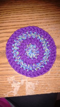 a purple crocheted doily sitting on top of a wooden table