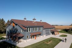 an aerial view of a large house with two people walking in the driveway near it