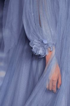 a woman's hand on the runway wearing a blue dress