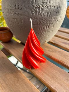 a red candle sitting on top of a wooden table next to a potted plant