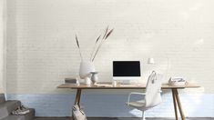 a desk with a computer on it in front of a white brick wall