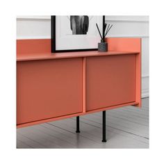 an orange sideboard with black metal legs in front of a framed photograph on the wall