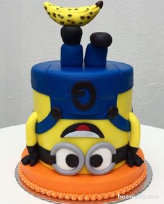 a yellow and blue cake with eyes and a banana on top