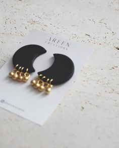 two pairs of black and gold earrings sitting on top of a card