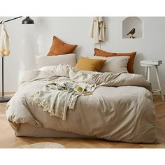 an unmade bed in a white room with wooden floors