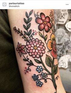 a woman's arm with flowers and leaves on it