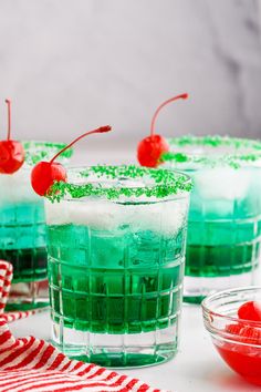 two glasses filled with green and red jello on top of a white tablecloth