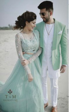 a man and woman standing next to each other on the beach