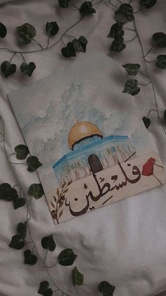 an image of a painting on a sheet with leaves surrounding it and the words in arabic