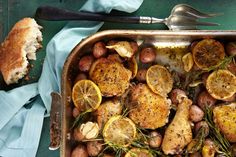 a pan filled with potatoes and lemons on top of a blue cloth next to a fork