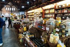 people are shopping in an open market with lots of food and spices on the shelves