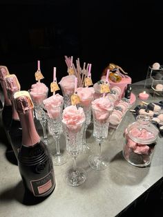 a table topped with lots of pink desserts and bottles of champagne next to each other