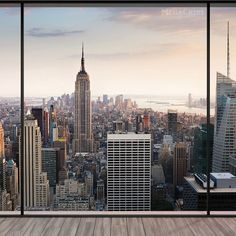 an empty room with cityscape in the background and floor to ceiling windows looking out onto new york