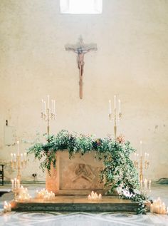 an altar with candles and greenery in front of a crucifix on the wall