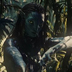 a woman with blue makeup and dreadlocks in the jungle