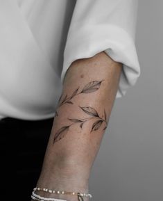 a woman's arm with a feather tattoo on it