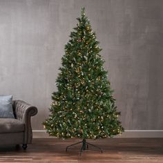 a living room with a couch and a christmas tree on the floor in front of a gray wall