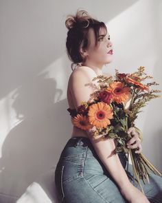 a woman sitting on the floor with flowers in her hand