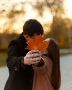 a man and woman holding an orange leaf