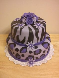 a zebra print cake with purple flowers on the top, and white lace around the edges