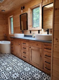 a large bathroom with two sinks and a tub in it's center, surrounded by wood paneling