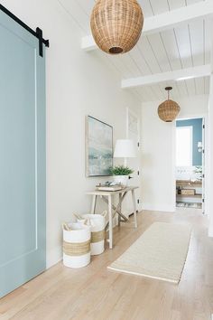 a room with white walls and wooden floors, two baskets on the floor next to a blue door