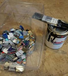 a can of paint next to a pile of scraps and a brush on the floor