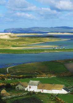 an aerial view of a farm and lake in the distance with mountains in the background