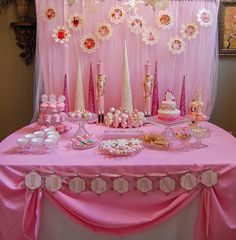 a pink table topped with lots of cakes and desserts