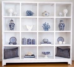 a white shelf filled with lots of blue and white vases on top of it