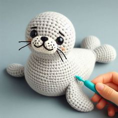 a crocheted stuffed seal with a toothbrush in it's mouth, sitting on a gray surface