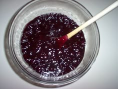 a glass bowl filled with blueberry sauce and a wooden stick in it's center