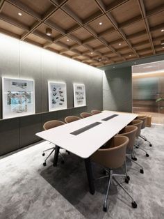 an empty conference room with chairs and pictures hanging on the wall above it's desk