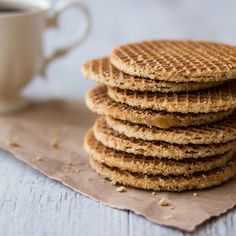 a stack of waffles sitting on top of a table next to a cup of coffee