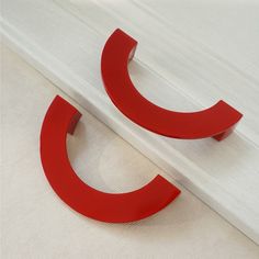 a pair of red metal letters sitting on top of a white table next to each other