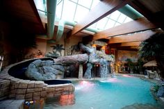 an indoor swimming pool with waterfall and slide