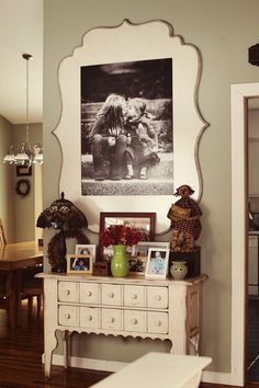 a white dresser with pictures on the wall