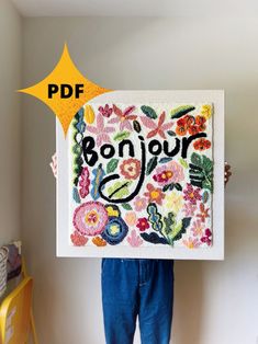 a person holding up a sign with the words bonjou written in floral designs on it