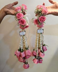 two hands are holding pink roses and other flowers