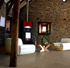 a living room filled with furniture and a fire place next to a wall covered in stone