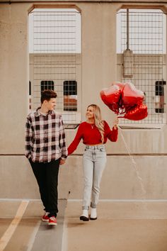 a young man and woman holding red balloons