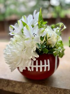 a football vase filled with white flowers and greenery