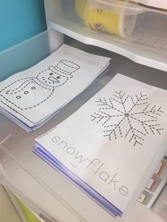 two snowflakes are sitting on the floor in front of a book shelf with other books