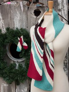 a knitted scarf on a mannequin next to a wreath